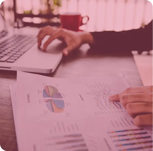 A group of people sitting around a table working on a laptop.