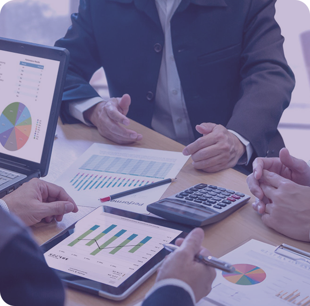 A group of people sitting around a table working on a laptop.